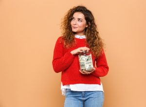 woman holds jar of money and wonders if it makes her an adult.