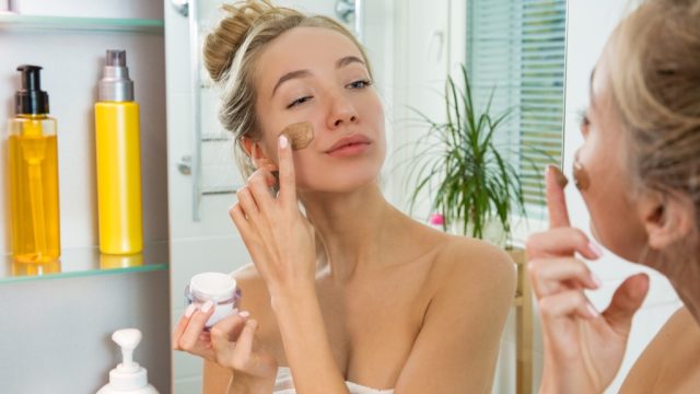woman putting on makeup in mirror