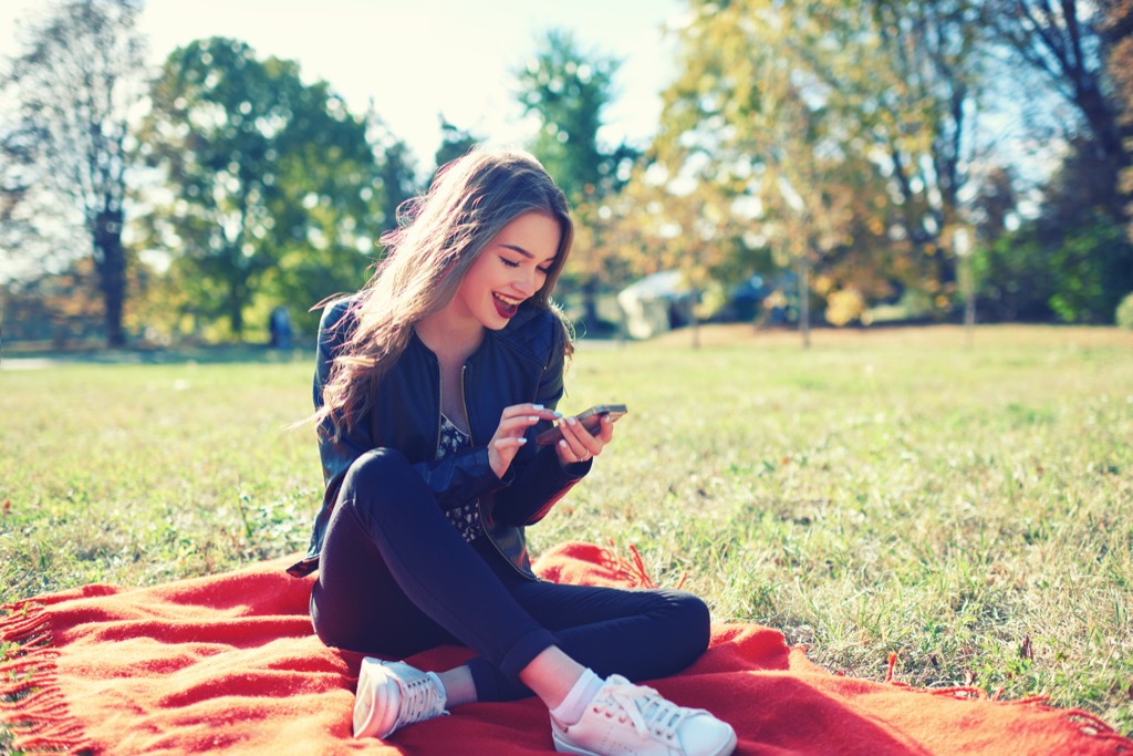 woman with smartphone in park Science-Based Happiness Hacks 
