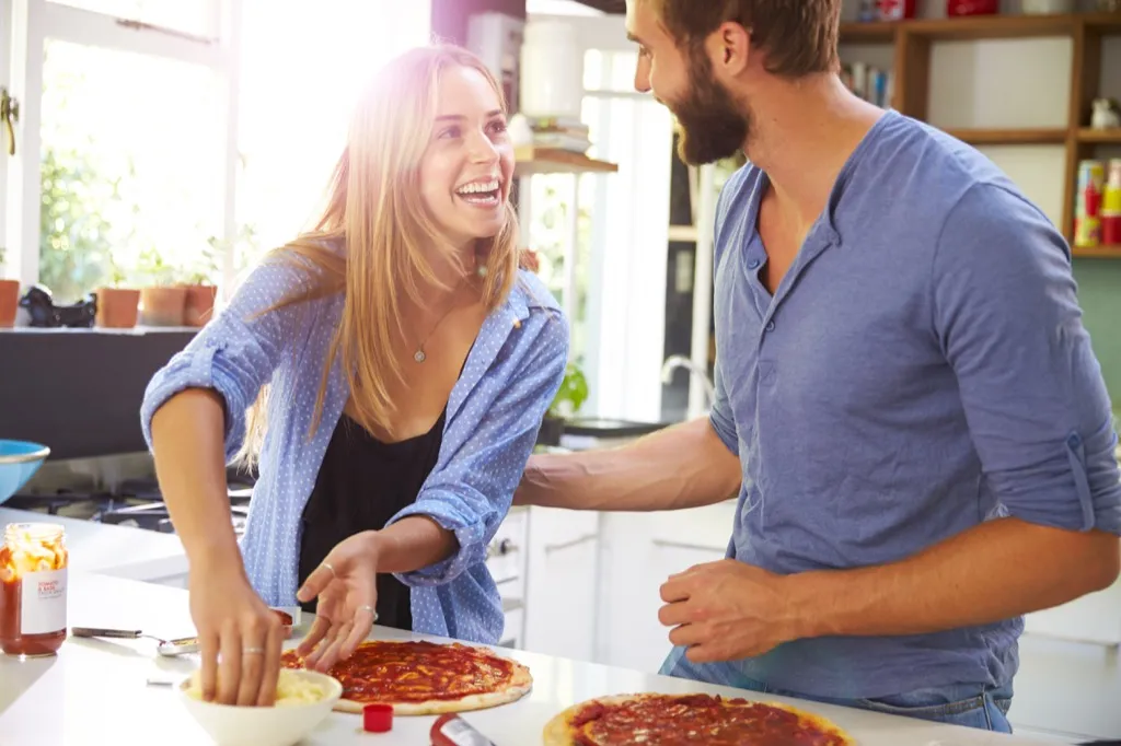 attractive couple making pizza at home