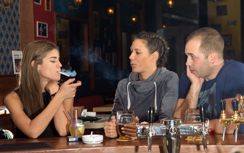 Friends at a bar smoking a cigarette