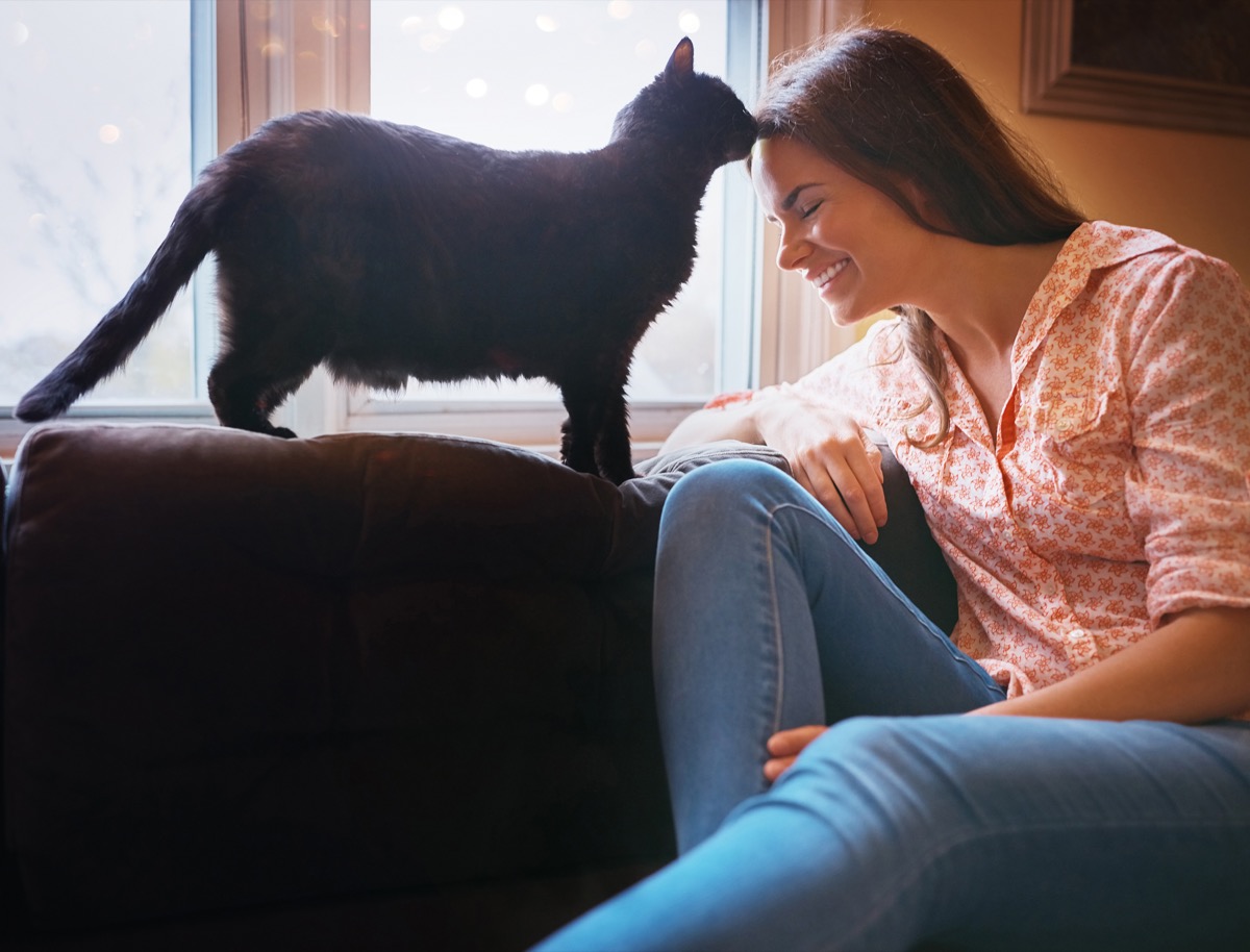 shot of an attractive young woman relaxing on the sofa at home and bonding with her cat