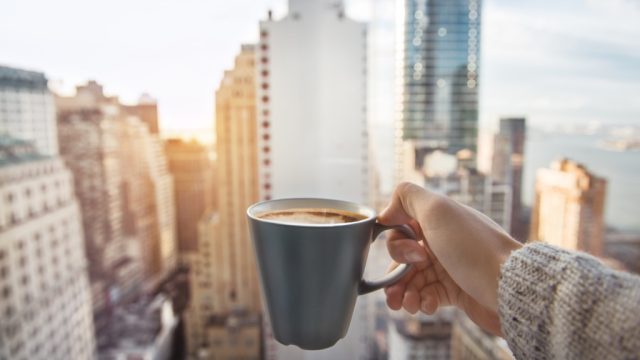 a cup of coffee in front of the manhattan new york skyline