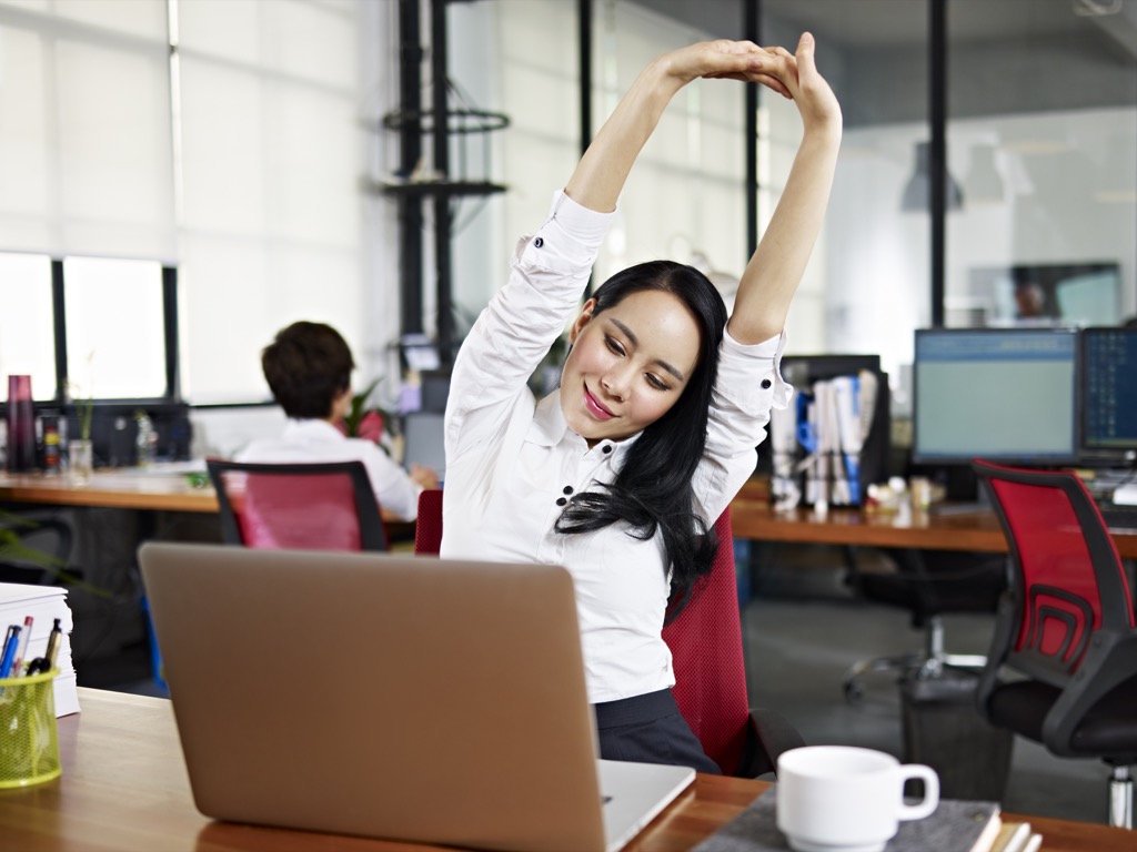 Woman being mindful and taking a deep breath at her desk