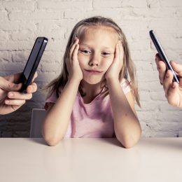 child sulks at parents flip through phones.