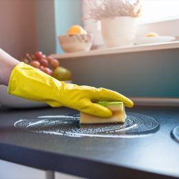 white person wearing gloves cleaning counters with sponge