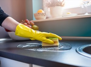 white person wearing gloves cleaning counters with sponge
