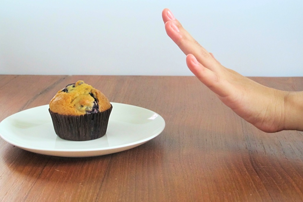Person rejecting a muffin, unhealthy habits