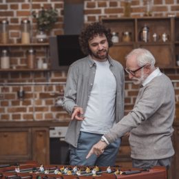 father and son pointing at table soccer game