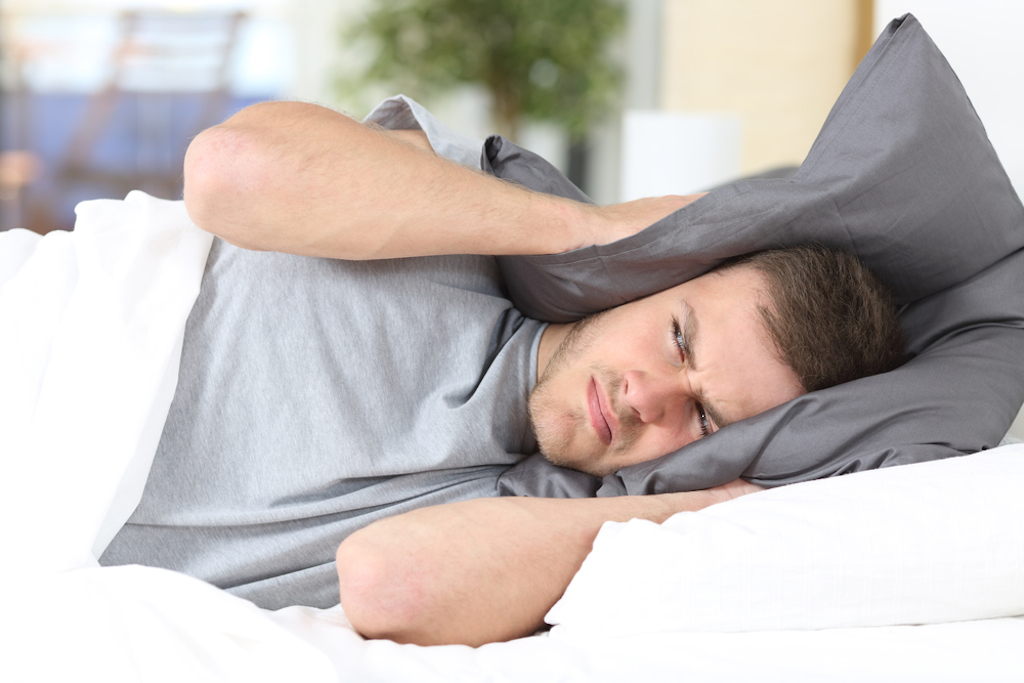 man trying to sleep angry about loud noise of neighbors