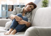 woman sad alone on couch ways we're unhealthy