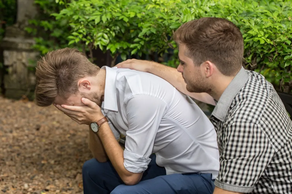 man comforts friend with head in hands