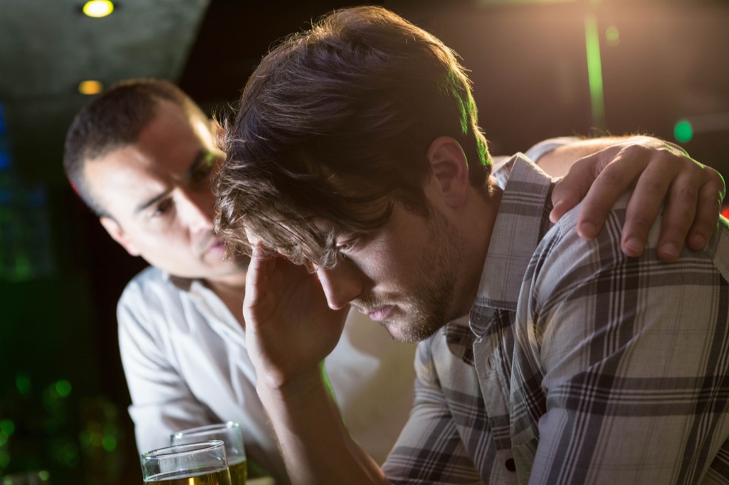 man checks on stressed friend at bar