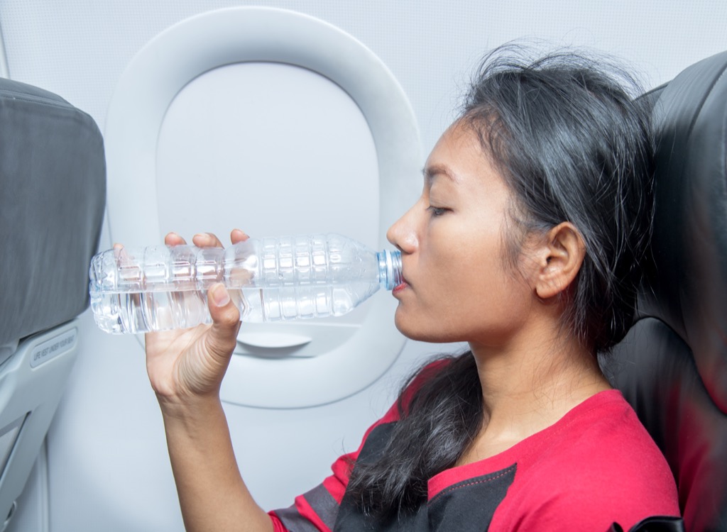 Woman drinking water on an airplane.