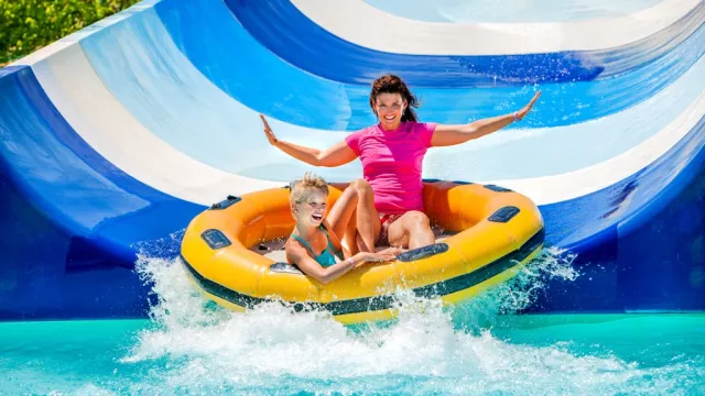 mother and son sliding down waterslide, water park