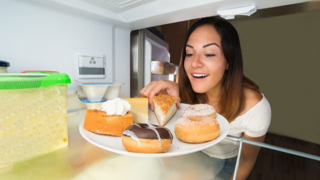 Woman overeating, eating in the fridge snacking