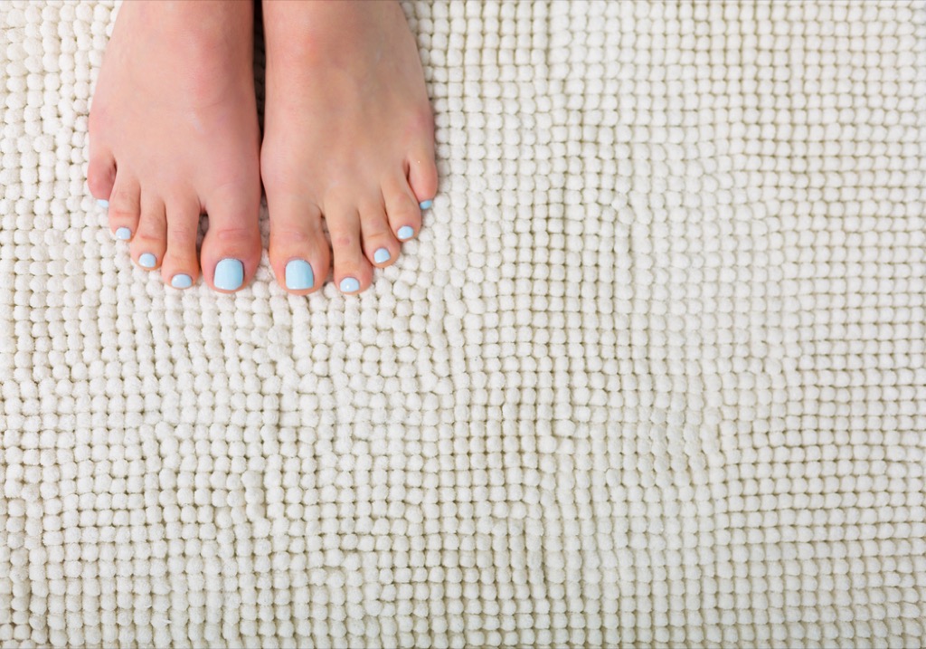 woman's feet on white bathroom rug, interior design mistakes