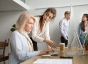 woman looking angry at older coworker on computer