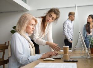 woman looking angry at older coworker on computer
