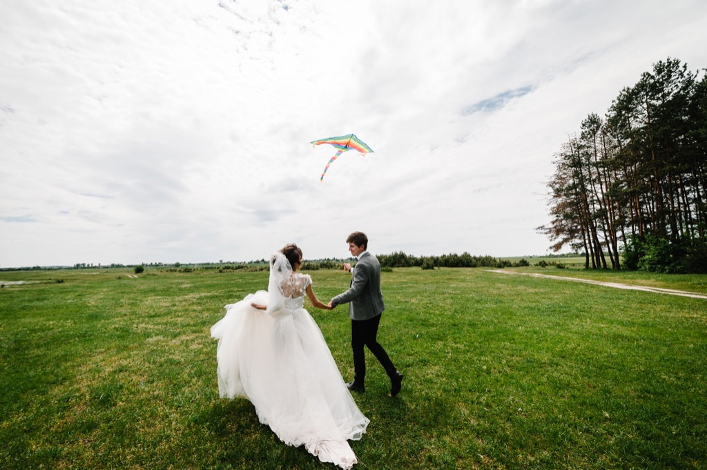 bride and groom running in field This Is the Age Most People Get Married in Every U.S. State