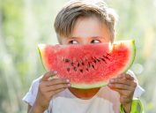 kid holding a watermelon in front of his face as if it is a smile, things you should never lie to kids about