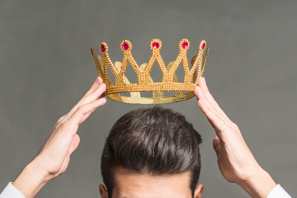 Man holding a crown above his head.