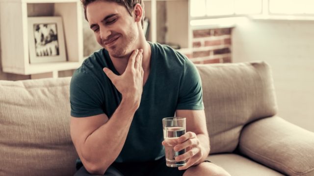 man holding a glass of water sitting on a couch