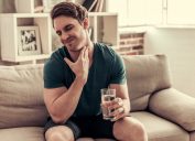 man holding a glass of water sitting on a couch