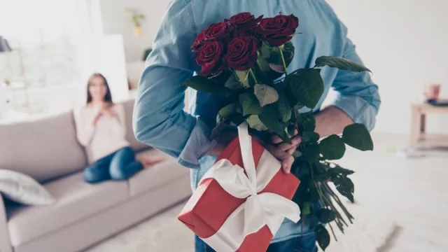 white man holding roses and a gift behind his back