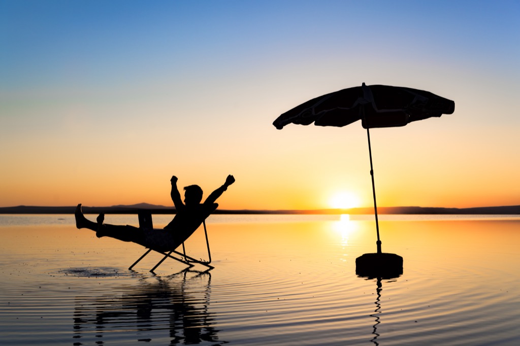 man relaxing on beach at sunset in a chair - funniest jokes 