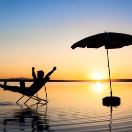man relaxing on beach at sunset in a chair - funniest jokes