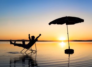 man relaxing on beach at sunset in a chair - funniest jokes