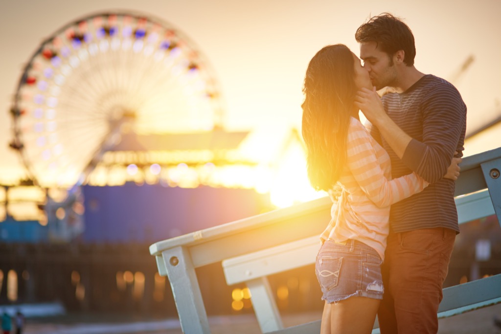 a man and woman kissing in front a ferris wheel