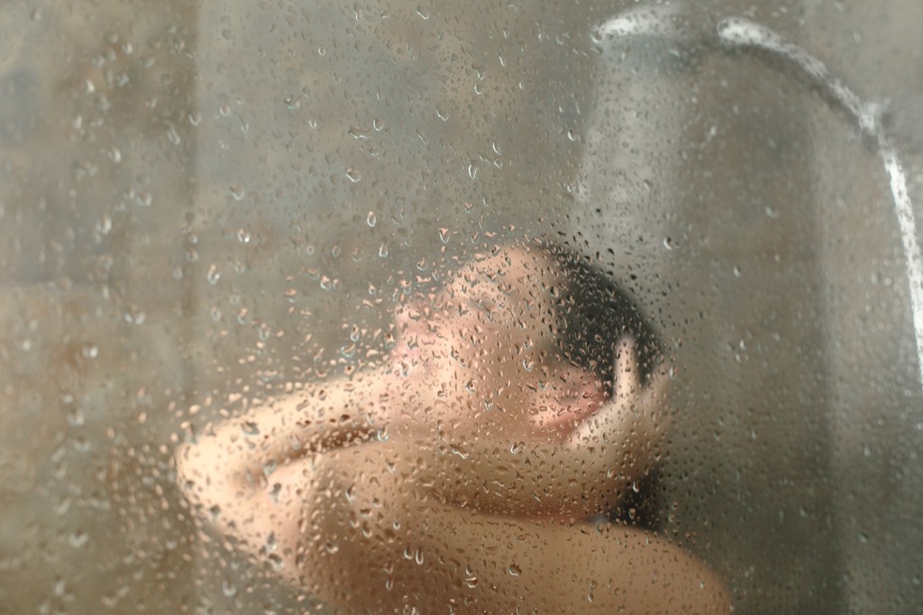 Woman in the shower behind the shower door lies over 40