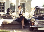 1950s-style woman sitting next to car