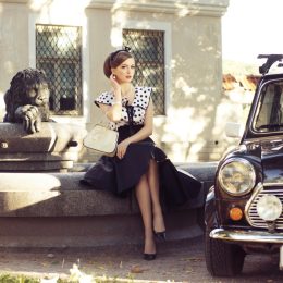 1950s-style woman sitting next to car