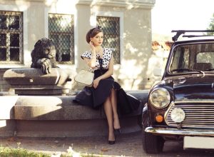 1950s-style woman sitting next to car