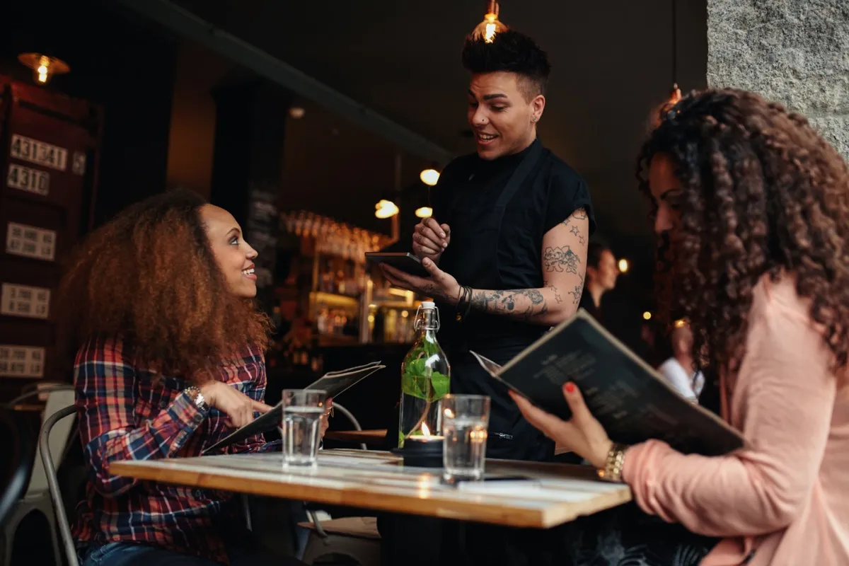 women ordering food from a waiter in a restaurant