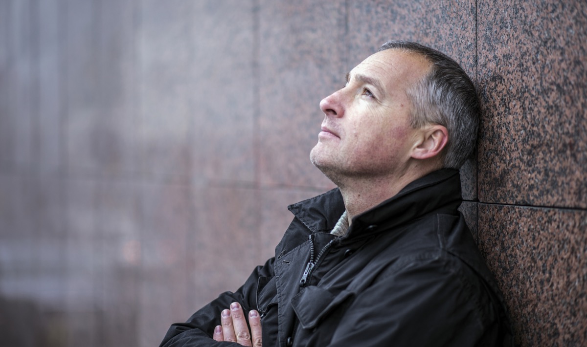 Mature man lost in thought standing outside and looking up