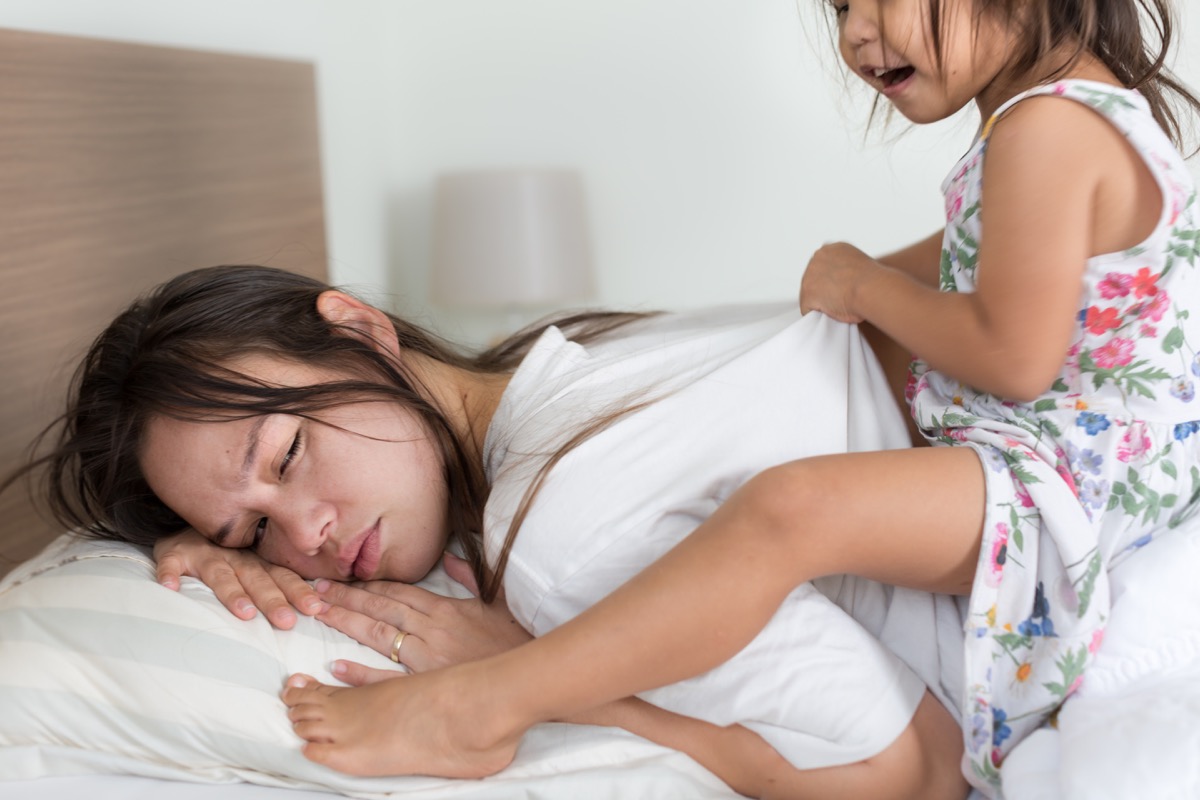 child on tired mother's back while she's trying to sleep