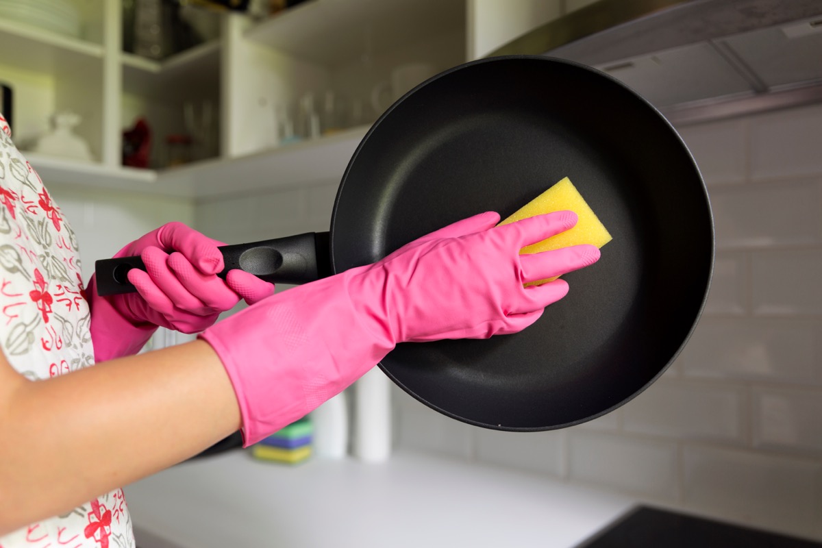 Woman Cleaning a Pan in the Kitchen Sink