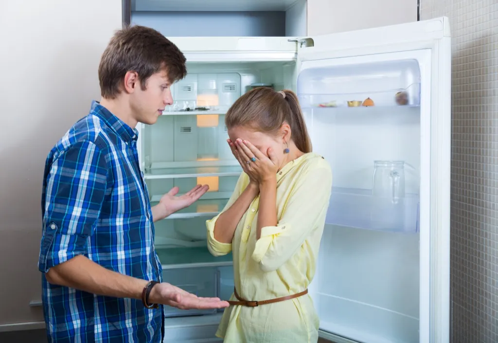couple arguing in front of a fridge
