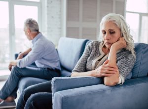 Older couple having an argument and fighting on the couch, over 50 regrets