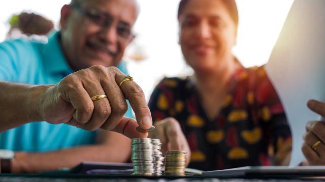 Senior Indian/asian couple arranging/staking coins/saving money