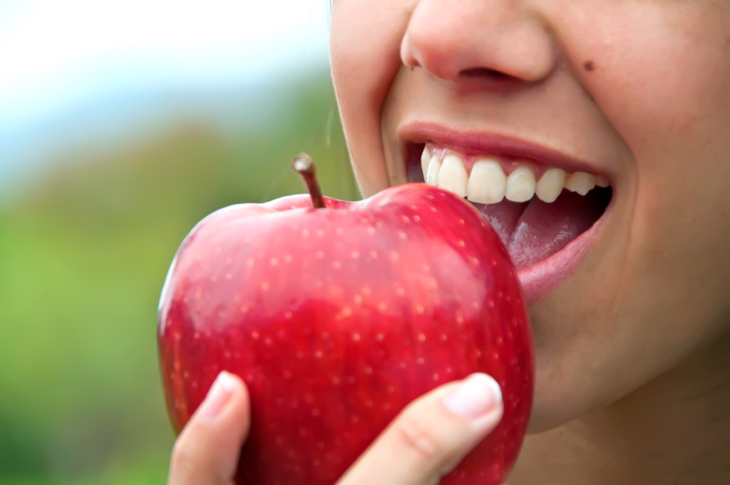 Woman eating an apple, biting into an apple