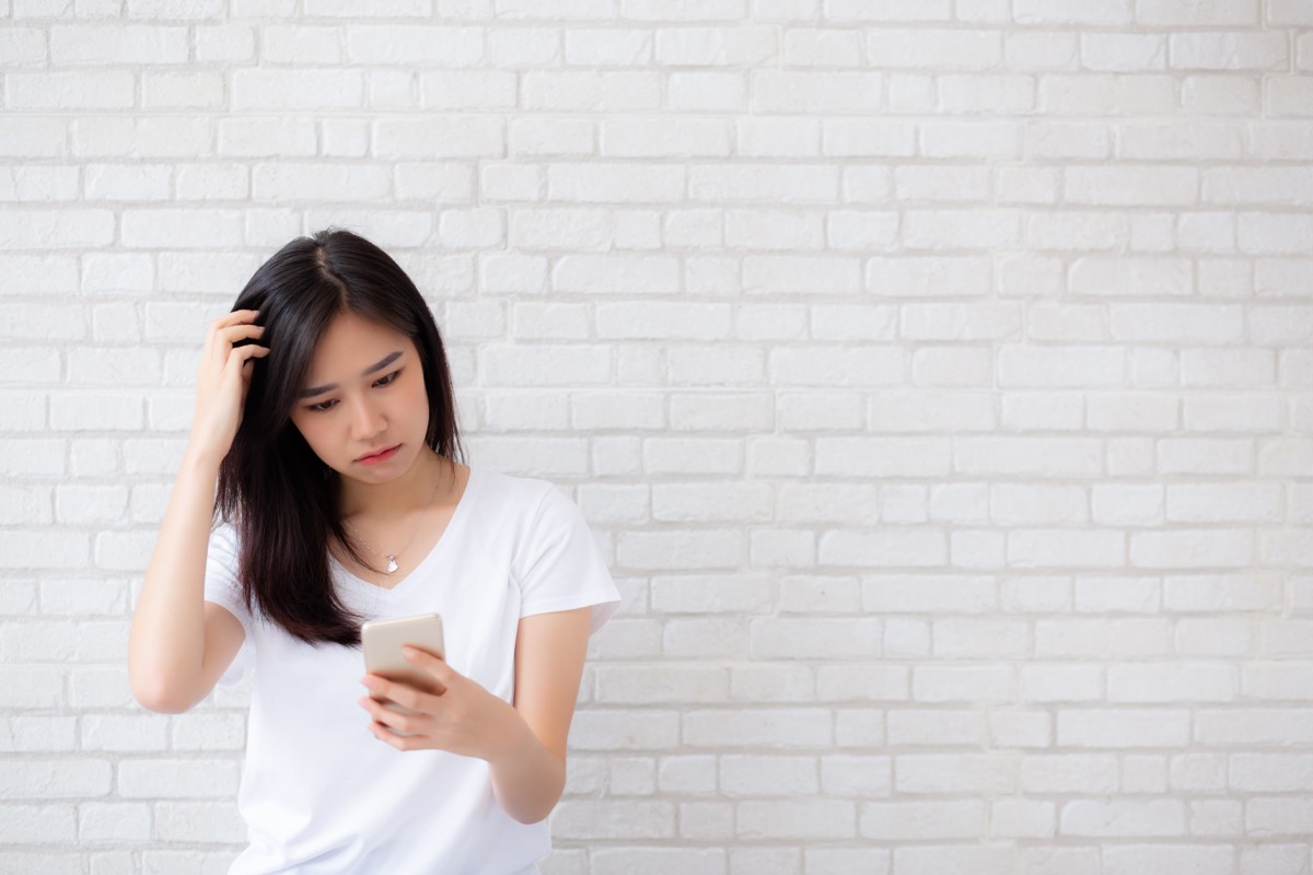 Stressed girl comparing herself to others on social media via cell phone