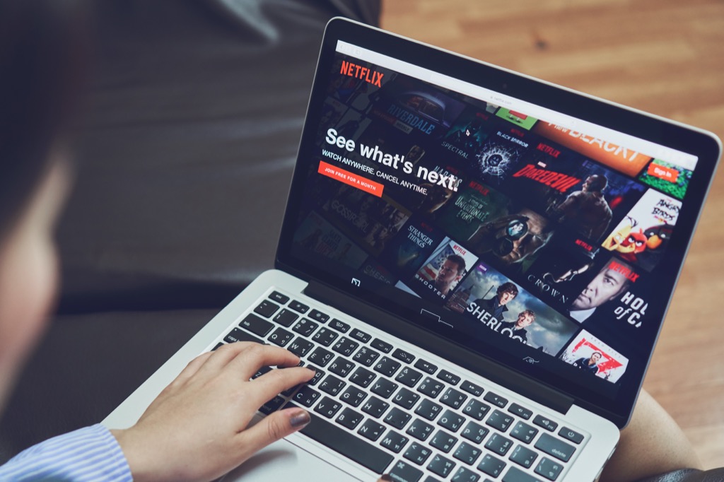 mężczyzna oglądający najlepsze filmy na Netflixie na swoim laptopie