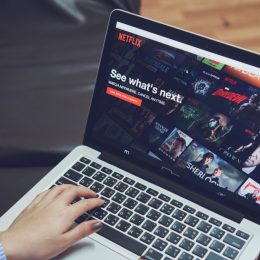 a man watching the best movies on netflix on his laptop