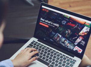 a man watching the best movies on netflix on his laptop