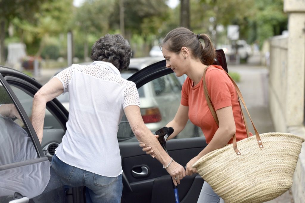 Woman helping a senior citizen get into the car